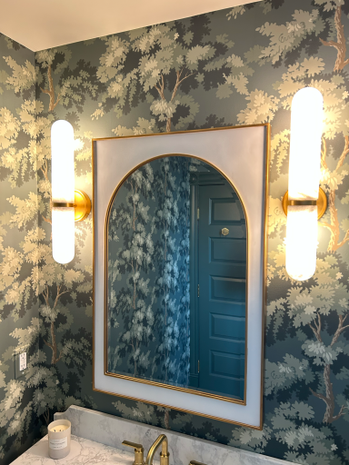 Wall with floral wallpaper, an arched mirror, and two modern light fixtures.